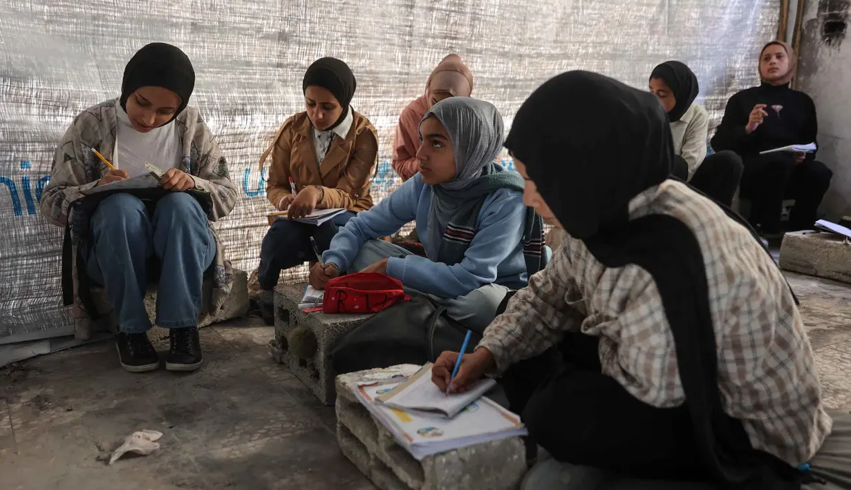 Untuk diketahui, sejak serangan Israel dimulai pada Oktober 2023, sistem pendidikan di Jalur Gaza telah mengalami kehancuran yang hampir menyeluruh. Tampak dalam foto, anak-anak pengungsi Palestina mengikuti belajar mengajar di dalam tenda di Sekolah Mada, kamp pengungsi Jabalia, Jalur Gaza Utara pada 13 April 2026. (Omar AL-QATTAA/AFP)