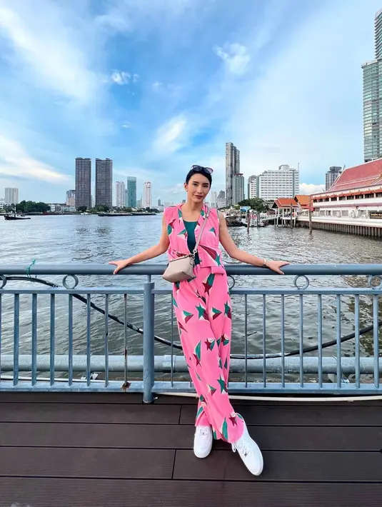 Tyas mengenakan set sleeveless top dan loose pants berwarna pink dengan motif bintang. Latar belakang sungai membuat penampilan Tyas terlihat segar. Tidak hanya berdua, Tyas dan Tengku Tezi diketahui berangkat bersama beberapa orang dalam sebuah rombongan. (Liputan6.com/IG/@tyasmirasih)