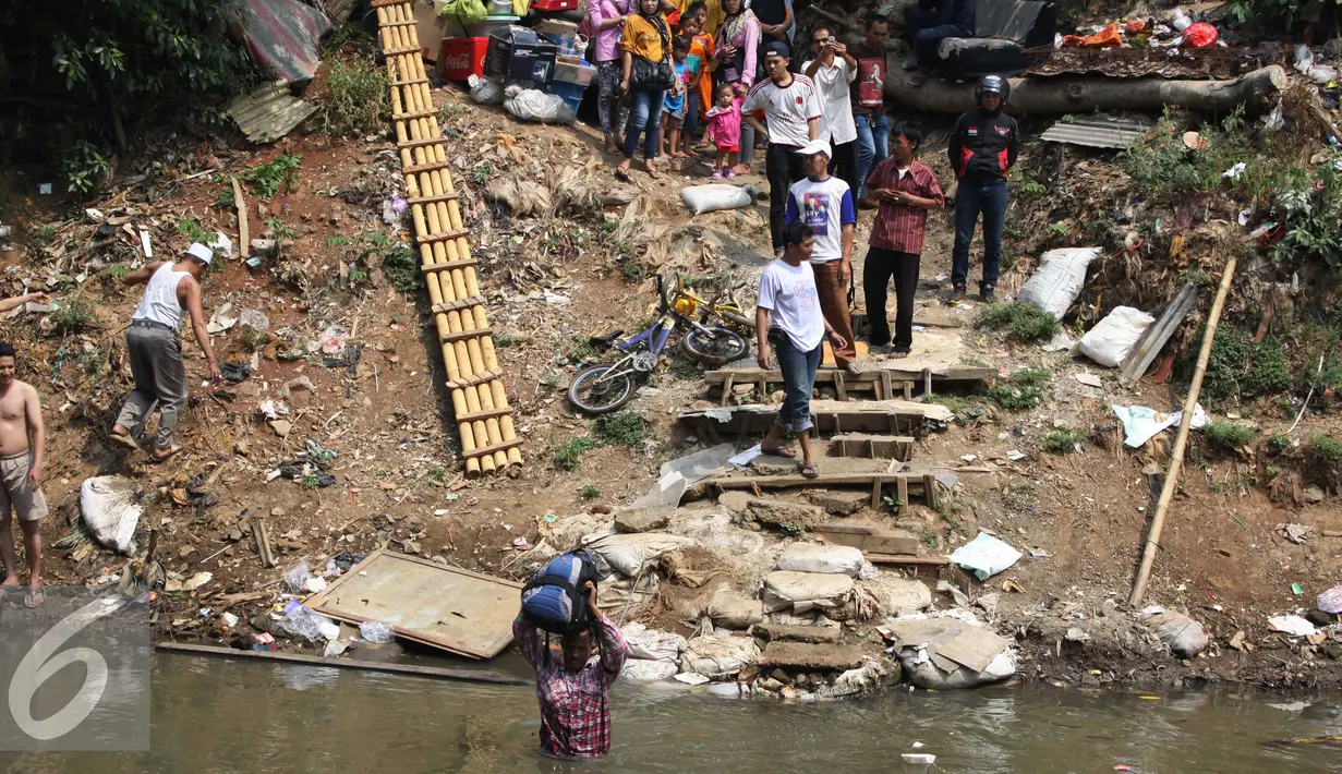 Seorang warga membawa barang miliknya menyeberangi kali Ciliwung usai penggusuran di Kampung pulo, Jakarta, Jumat (21/8/2015). Penggusuran terkait rencana Pemprov DKI Jakarta yang akan melakukan normalisasi Kali Ciliwung. (Liputan6.com/Gempur Surya)