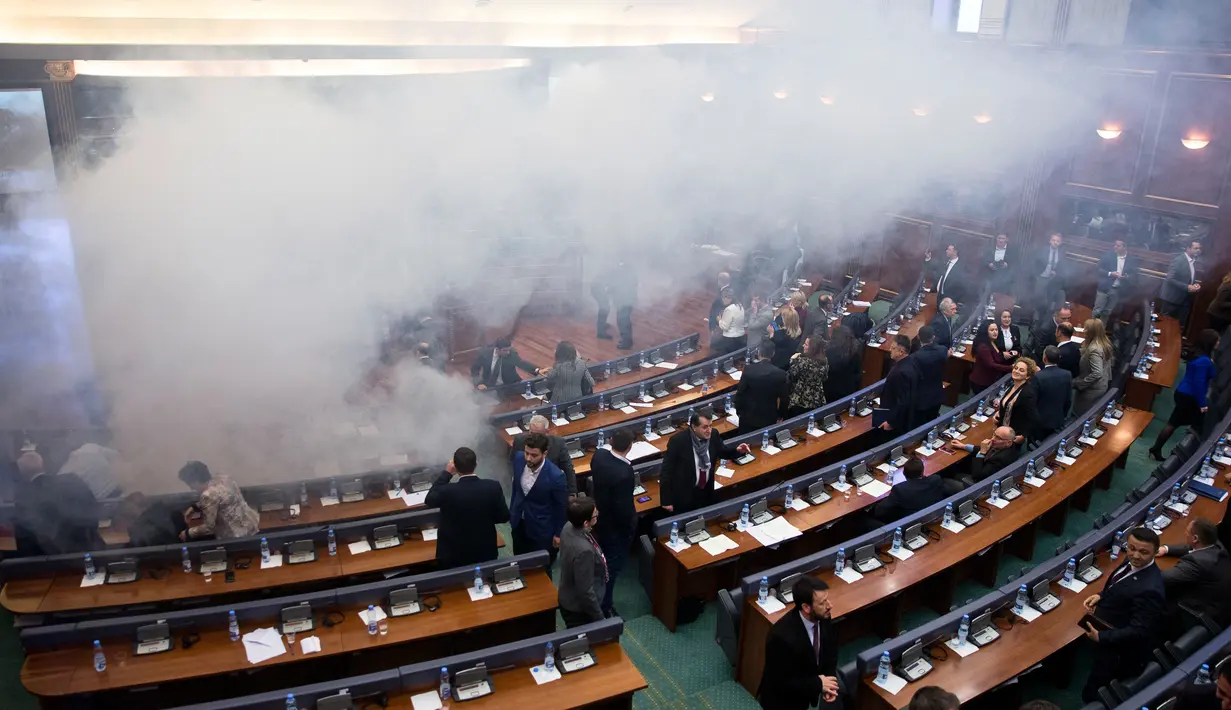 Para politisi meninggalkan ruangan yang dipenuhi asap gas air mata dalam rapat parlemen di ibu kota Kosovo, Pristina, Rabu (21/3). Aksi pelemparan kaleng gas air mata tersebut dilakukan oleh seorang anggota Partai Vatevendosje. (AP Photo/Visar Kryeziu)