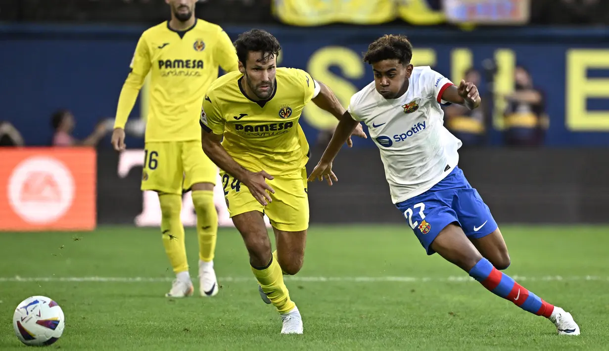 Pemain Barcelona, Lamine Yamal, berusaha melewati pemain Villarreal, Alfonso Pedraza, pada laga Liga Spanyol 2023/2024 di Stadion La Ceramica, Minggu (27/8/2023). Barca menang dengan skor 4-3. (AFP/Javier Soriano)