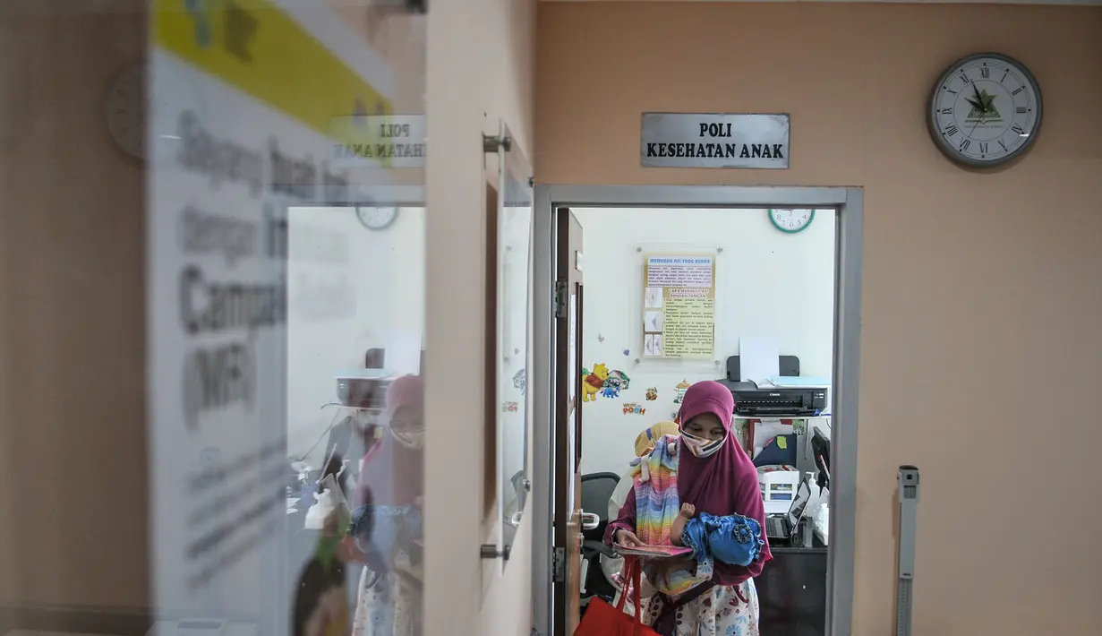 Seorang ibu bersama anaknya usai mengikuti imunisasi di Puskesmas Kecamatan Jatinegara, Jakarta, Kamis (26/11/2020). (merdeka.com/Iqbal S. Nugroho)