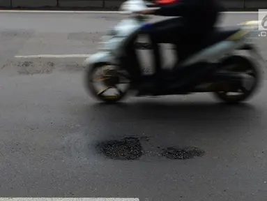 Pengendara motor melintas menghindari jalan berlubang di Jalan Gunung Sahari, Jakarta, Selasa (9/4). Meskipun sudah dilakukan penambalan, jalan raya tersebut sering rusak akibat beban kendaraan yang melintas di atasnya dan intensitas hujan yang belakangan ini cukup tinggi. (merdeka.com/Imam Buhori)