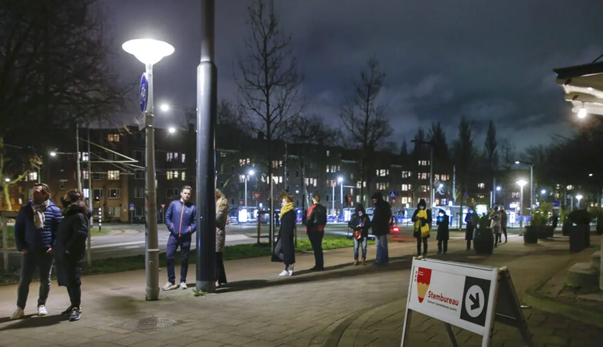 Warga mengantre untuk memberikan suara di luar TPS pada jam terakhir pemungutan suara dalam pemilihan umum di Amsterdam, Belanda, Rabu (17/3/2021). Pemilu digelar selama tiga hari untuk memungkinkan warga memilih dengan aman selama pandemi virus corona COVID-19. (AP Photo/Peter Dejong)