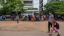 Pejalan kaki melewati warga yang berkumpul di depan kantor Imigrasi dan Emigrasi untuk mengurus paspor di Kolombo, Sri Lanka, Senin (18/7/2022). Negara kepulauan Samudra Hindia itu dilanda krisis ekonomi yang belum pernah terjadi sebelumnya yang telah memicu ketidakpastian politik. (Photo by Arun SANKAR / AFP)
