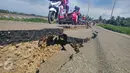Sejumlah warga mengendarai sepeda motor melintas di jalan yang retak di Kabupaten Pidie Jaya, Aceh, Kamis (8/12). Gempa berkekuatan 6,5 SR pada Rabu pagi menyebabkan sejumlah ruas jalan retak dan mengalami kerusakan. (Liputan6.com/Angga Yuniar)