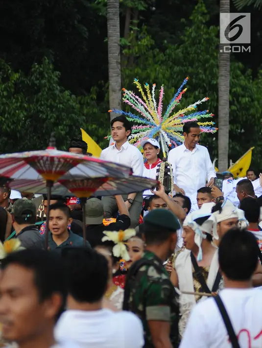 Capres 01 Joko Widodo didampingi Iriana Jokowi dan Kaesang Pangarep melempar kaus seusai 'Konser Putih Bersatu' di Stadion GBK, Jakarta, Sabtu (13/4). Pasangan Capres dan Cawapres 01 menggunakan kereta kencana seusai Konser Putih Bersatu menuju lokasi debat. (Liputan6.com/Herman Zakharia)