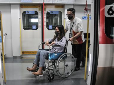 Petugas Light Rail Transit (LRT) Jakarta membantu mendorong kursi roda penumpang disabilitas dalam rangkaian gerbong kereta menggunakan kursi roda di Stasiun Pegangsaan Dua, Jakarta Utara, Selasa (24/1/2023). LRT Jakarta melakukan kampanye #NyamankanJakarta. (merdeka.com/Iqbal S. Nugroho)