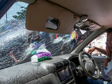 Seorang pengemudi menutupi wajahnya setelah dipukul massa demo transportasi online di JMakassar, Sulawesi Selatan, (1/11). Para sopir angkutan konvensional di Makassar melakukan aksi menuntut maraknya transportasi online. (AFP Photo/Yusuf Wahil)
