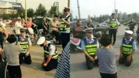 Dua orang polisi tampak berlutut ketika hendak menilang seorang ibu (foto: Weibo)