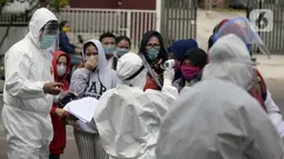 Petugas Puskesmas memeriksa suhu warga yang mengikuti swab test di Balai RW 20, Villa Dago, Pamulang, Tangerang Selatan, Banten, Jumat (17/7/2020). Swab test gratis yang digelar seiring meningkatnya kasus COVID-19 tersebut diikuti 200 warga dari beberapa RW di Benda Baru. (merdeka.com/Dwi Narwoko)