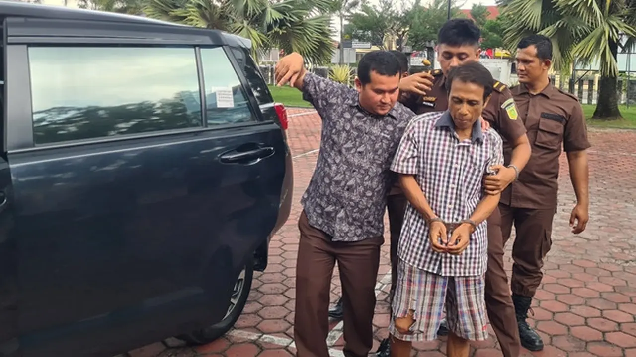 Petugas Kejari Bengkalis menggiring tersangka korupsi jual beli lahan negara yang sempat menjadi buronan.