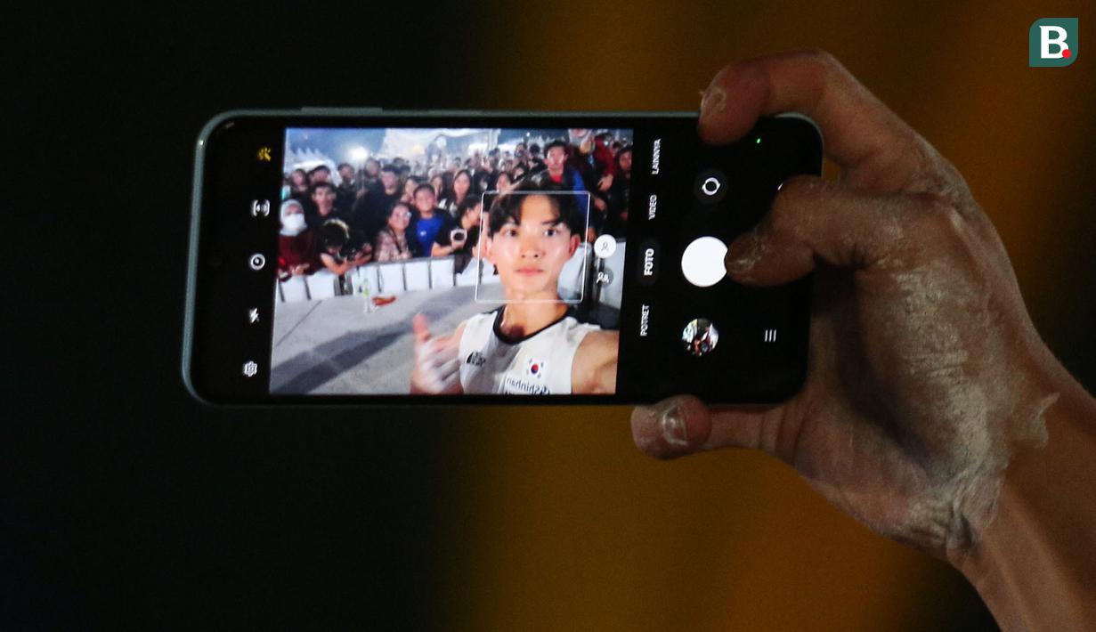 Atlet panjat tebing Korea Selatan berswa foto bersama penonton saat Kejuaraan Dunia Panjat Tebing IFSC 2023 seri Jakarta melawan atlet panjat tebing China, Xinshang Wang di Lot 6, Kompleks Stadion Utama Gelora Bung Karno, Jakarta, Indonesia, Minggu (07/05/2023). Raharjati berhasil mencatatkan waktu 5,11 detik. (Bola.com/Bagaskara Lazuardi)