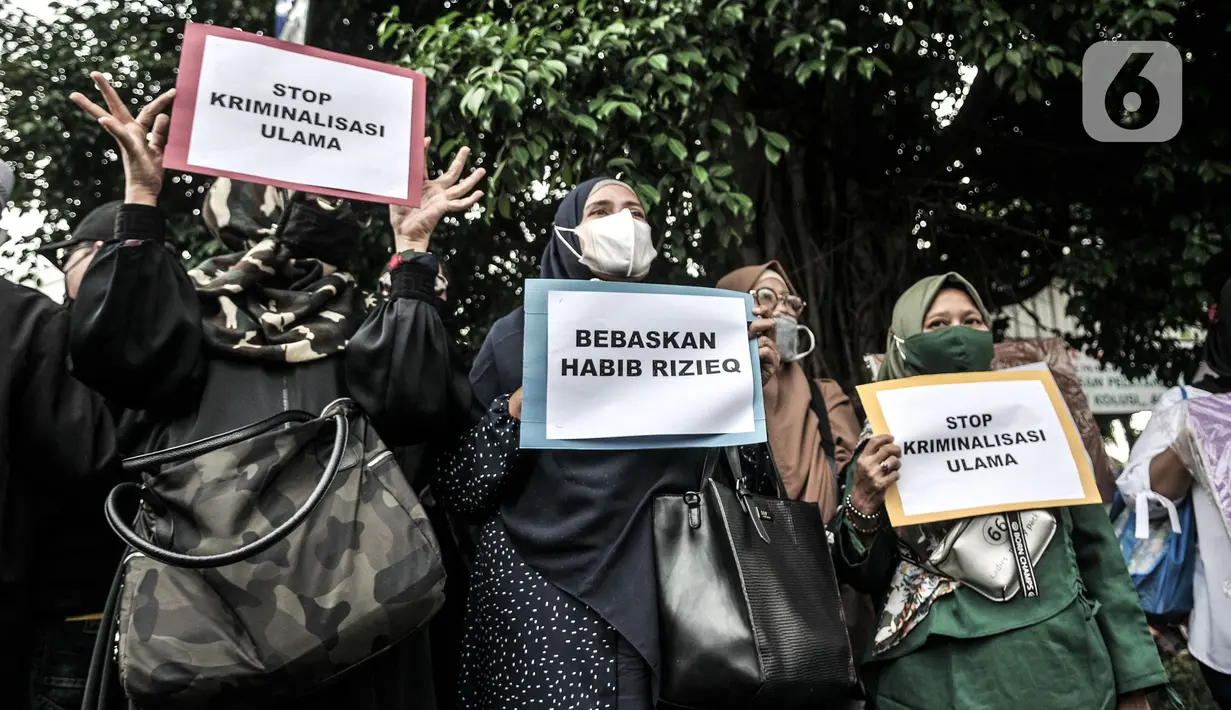 Massa pendukung membawa poster saat sidang perdana Rizieq Shihab di Pengadilan Negeri Jakarta Timur, Jakarta, Selasa (16/3/2021). Massa mendatangi PN Jakarta Timur untuk menyaksikan sidang Rizieq Shihab terkait kasus kerumunan dan tes usap meski digelar secara virtual. (merdeka.com/Iqbal S. Nugroho)