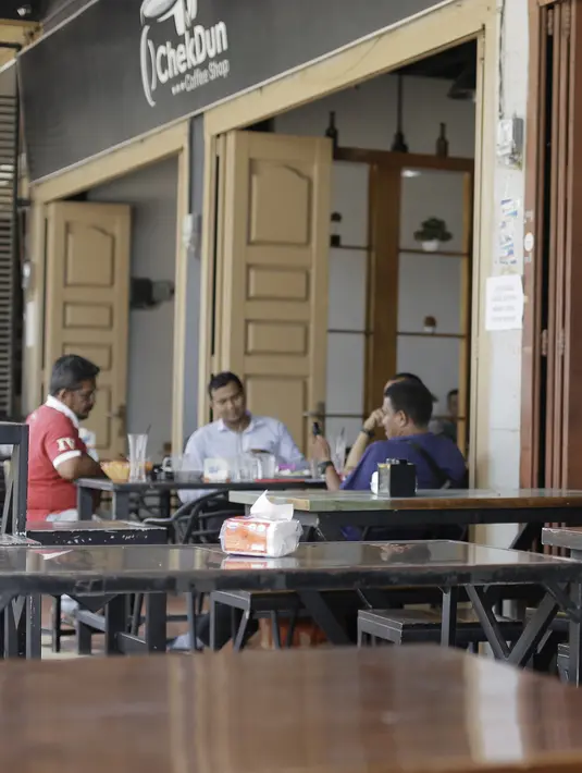 Pengunjung duduk di sebuah restoran di Bireuen, Aceh, Rabu (5/9). Selain larangan duduk bersama nonmuhrim, Pemerintah Kabupaten Bireuen juga mengeluarkan surat edaran pramusaji perempuan dilarang bekerja di atas pukul 21.00 WIB. (AFP PHOTO/AMANDA JUFRIAN)