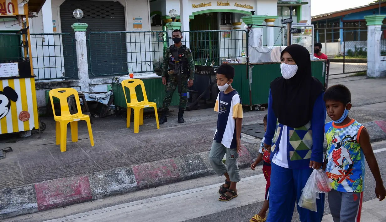 Seorang wanita yang mengenakan masker berjalan bersama anak-anak saat membeli makanan di pasar menjelang berbuka puasa selama bulan suci Ramadan di Provinsi Narathiwat, Thailand, Selasa (5/5/2020). Ramadan kali ini berlangsung di tengah bayang-bayang virus corona COVID-19. (Madaree TOHLALA/AFP)