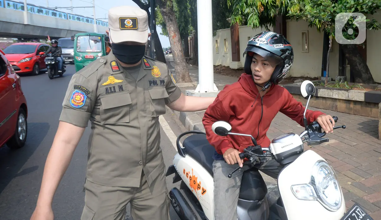 Petugas memberhentikan pengandara motor saat operasi yustisi protokol kesehatan untuk meningkatkan kesadaran dan kedisiplinan warga di Lebek Bulus, Jakarta, Senin (14/9/2020). Pemprov DKI memperketat kembali PSBB karena kasus Covid-19 mengalami peningkatan. (merdeka.com/Dwi Narwoko)