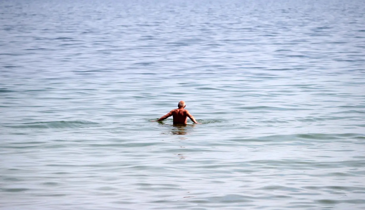 Seorang pria berenang di laut Baltik di Gdynia, Polandia utara (24/5/2019). Dalam bahasa Jerman, laut ini disebut Ostsee yang sebenarnya berarti "laut Timur". (AP Photo/Darko Vojinovic)
