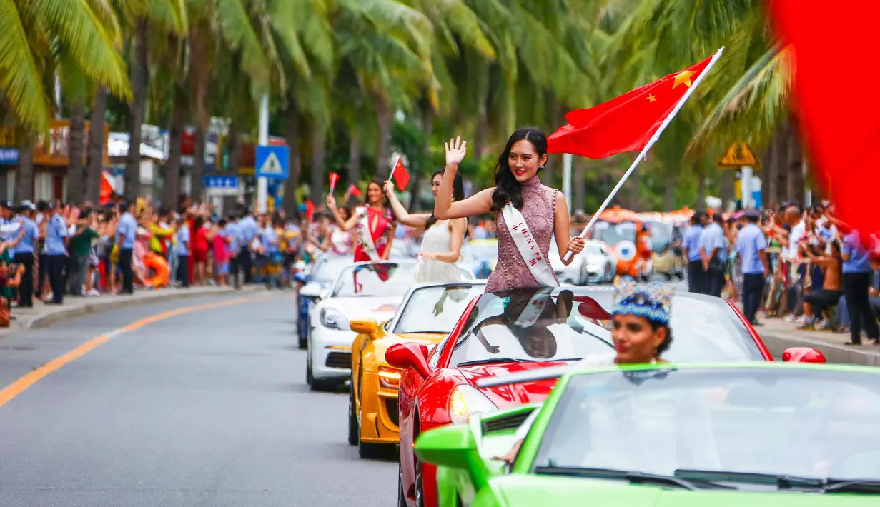 Kontestan Miss World dari China tersenyum sambil membawa bendera China saat mengikuti pawai menggunakan supercar di Sanya, Provinsi Hainan, China, (7/11). Pawai ini membuka kontes kecantikan Miss World ke-67. (AFP Photo/Str/China Out)