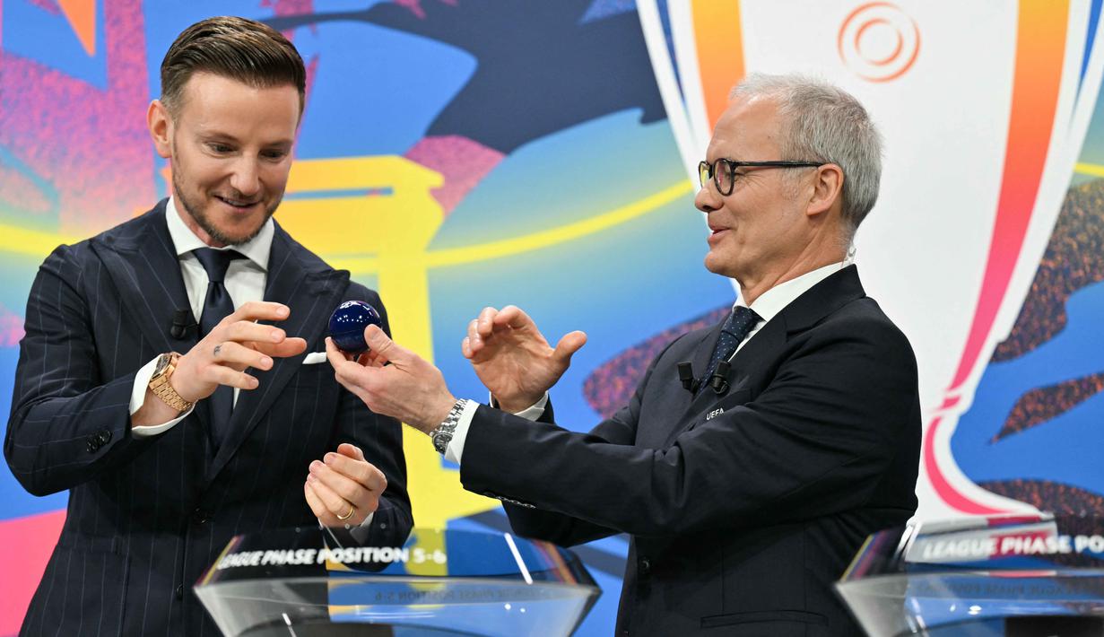 Melalui pengundian ini, setiap tim akan mengetahui potensi lawan mereka selanjutnya. Tampak dalam foto, Wakil Sekretaris Jenderal UEFA Giorgio Marchetti (kanan) menyerahkan bola undian kepada duta Yayasan UEFA untuk Anak-Anak yang juga mantan gelandang Sevilla, Ivan Rakitic, selama pengundian babak 16 besar, perempat final, dan semifinal Liga Champions 2025/2026 di House of European Football di Nyon, Swiss, Jumat (27/2/2026). (Harold CUNNINGHAM/AFP)