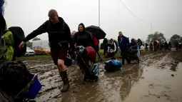 Penonton Festival Glastonbury tampak melewati jalanan yang banjir dan berlumpur saat tiba di Worthy Farm, Somerset, Inggris , (22/6).Meski cuaca hujan, Para penonton tetap akan menyaksikan festival musik paling populer di dunia. (REUTERS / Stoyan  Nenov)