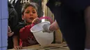 Seorang anak yang membutuhkan menerima makanan berbuka puasa dari juru masak di dapur Masjid Muslim Sunni Abdel Kader al-Kilani, Baghdad, Irak, 19 April 2021. Kegiatan ini berlangsung selama bulan suci Ramadhan. (AHMAD AL-RUBAYE/AFP)