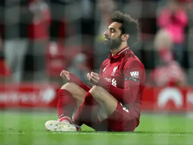 Winger Liverpool, Mohamed Salah duduk di depan gawang setelah mencetak gol ke gawang Huddersfield Town dalam laga lanjutan Premier League 2018-19 pekan ke-36 di Anfield, Jumat (26/4). Bermain di kandang sendiri, Liverpool menang dengan skor telak 5-0.  (AP Photo/Jon Super)