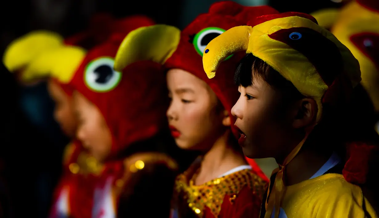 Anak-anak mengenakan kostum ayam saat perayaan menjelang tahun baru China di Lisbon, Portugal (21/1). Di Portugal, menjelang perayaan Imlek, warga keturunan Tionghoa merayakan dengan karnaval di sekitar jalan Kota Lisbon. (AFP/Patricia De Melo Moreira)