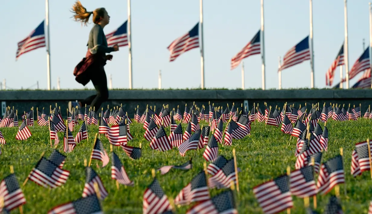 Aktivis dari COVID Memorial Project meletakkan ribuan bendera Amerika berukuran kecil di di halaman National Mall di Washington, Selasa (22/9/2020). Ribuan bendera itu menandai 200 ribu nyawa yang hilang akibat virus corona Covid-19 di Amerika Serikat. (AP Photo/J. Scott Applewhite)