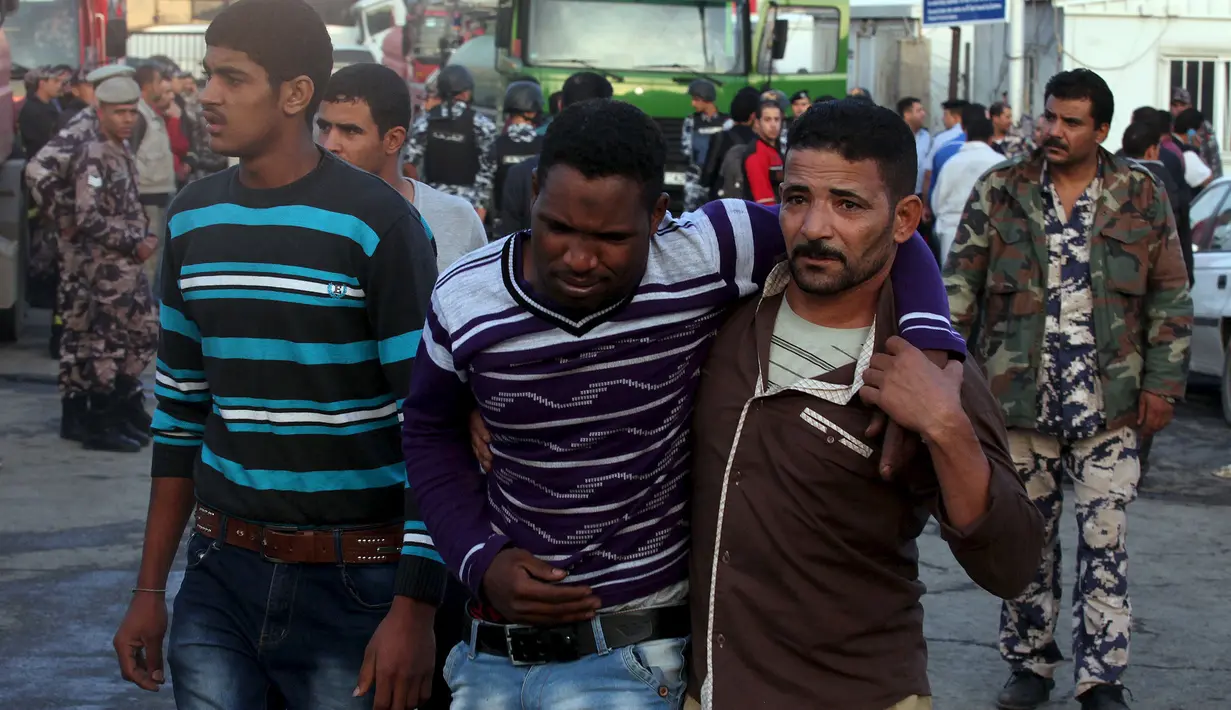 Warga membantu korban luka akibat meledaknya dua kontainer yang membawa kembang api di halaman departemen bea cukai di Amman, Yordania, Senin (26/10). Kejadian tersebut menewaskan delapan orang dan 12 lainnya terluka. (REUTERS/Stringer)