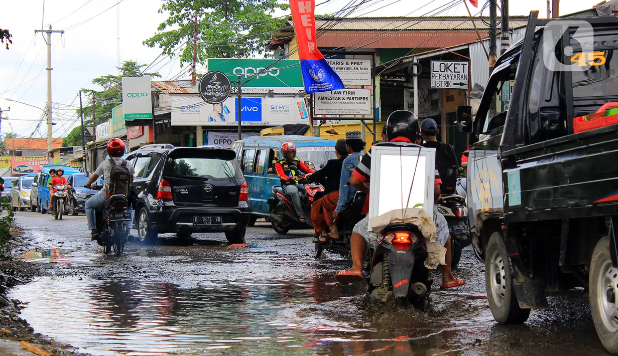 Kendaraan menerobos lubang yang ada di Jalan Raya Bojonggede, Bogor, Jawa Barat, Sabtu (22/2/2020). Jalan Raya Bojonggede yang berlubang hingga kini belum juga diperbaiki pemerintah setempat membuat kondisi lalu lintas tersendat (merdeka.com/Magang/Muhammad Fayyadh)