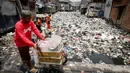 Pedagang melintas saat petugas mengangkut sampah yang menumpuk di Kali Gendong, Penjaringan, Jakarta, Kamis (16/3). Ceceran sampah plastik limbah rumah tangga terlihat menyerupai daratan menumpuk di sepanjang Kali Gendong. (Liputan6.com/Faizal Fanani)
