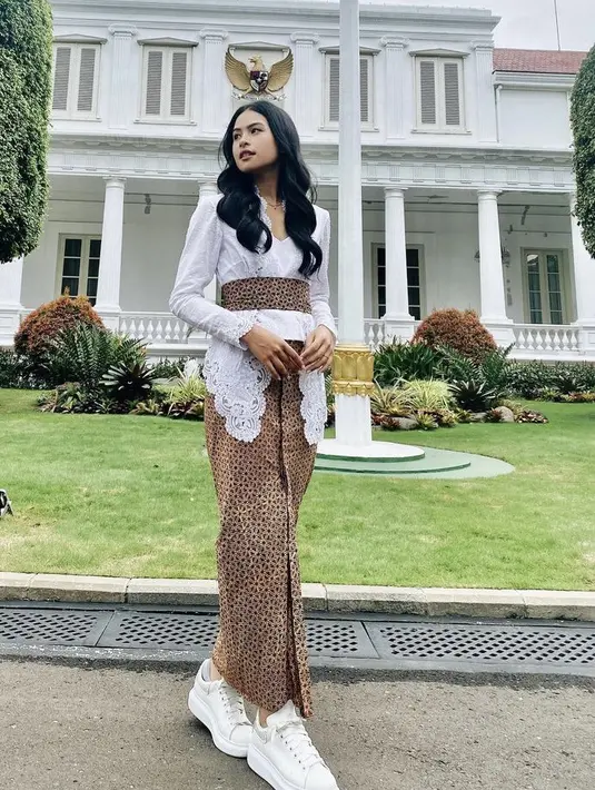 Maudy Ayunda mengenakan kebaya putih panjang dipadukan obi dan kain batik warna dan corak serasi.  Lebih kasual dengan sneakersnya. [Instagram/@maudyayunda]