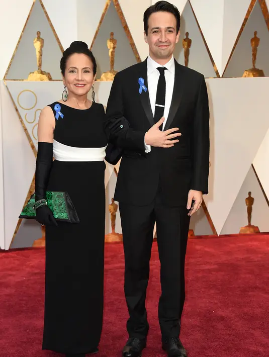 Lin Manuel-Miranda ditemani sang ibu, Dr. Luz Towns-Miranda, berpose di karpet merah ajang penghargaan Piala Oscar 2017 di Los Angeles, Minggu (26/2). Luz Towns-Miranda juga terlihat menyematkan pita biru di gaunnya. (Photo by Jordan Strauss/Invision/AP)