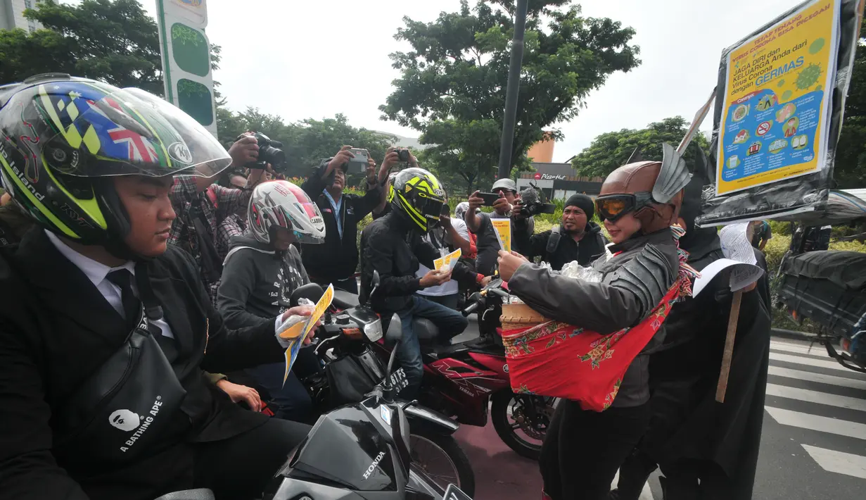 Warga mengenakan kostum superhero Gundala dan Batman saat melakukan aksi sosialisasi pencegahan virus corona di Solo, Rabu (4/3/2020). Dalam aksinya mereka membagikan jamu gratis kepada para pengguna jalan untuk meningkatkan daya tahan agar terhindar dari berbagai penyakit.  (AFP Photo/Anwar Mustafa