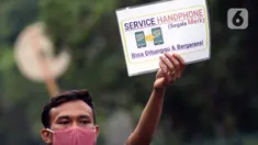 Penjual jasa perbaikan telepon genggam menawarkan jasanya di depan Mall Pusat Grosir Cililitan, Jakarta, Kamis (14/5/2020). Sejak pemberlakuan Pembatasan Sosial Berskala Besar yang berimbas pada penutupan pusat-pusat perbelanjaan, pendapatan mereka turun drastis. (Liputan6.com/Helmi Fithriansyah)