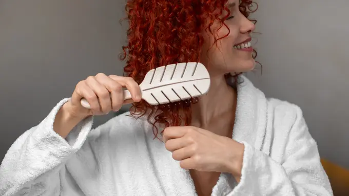 Seorang perempuan menyisir rambut keritingnya (Foto Dok: Freepik/freepik)