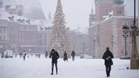 Sejumlah warga berjalan di Kota Tua saat hujan salju pertama mengguyur Warsawa, Polandia, pada 10 Desember 2020. Warsawa menyambut salju pertamanya tahun ini pada Kamis (10/12). (Xinhua/Jaap Arriens)