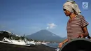 Nelayan membawa hasil tangkapannya dengan latar Gunung Agung di kawasan Amed, Karangasem, Bali, Kamis (7/12). Sepekan terakhir, aktivitas Gunung Agung mulai tampak tenang, meskipun masih status Awas. (Liputan6.com/Immanuel Antonius)