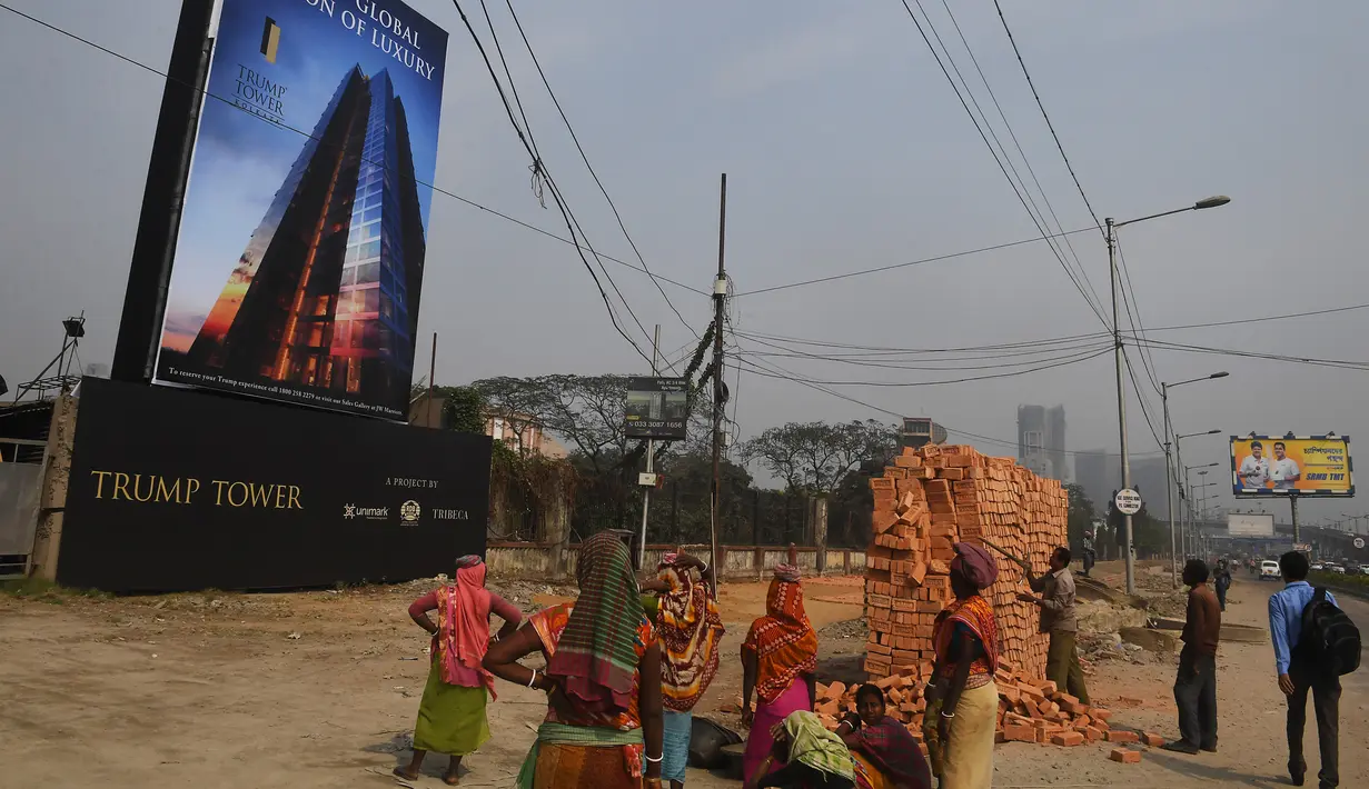 Buruh wanita India berkumpul sebelum mengangkat bata untuk pembangunan konstruksi Trump Tower atau Menara Trump di Kolkata, India (20/2). (AFP/ Dibyangshu Sarkar)