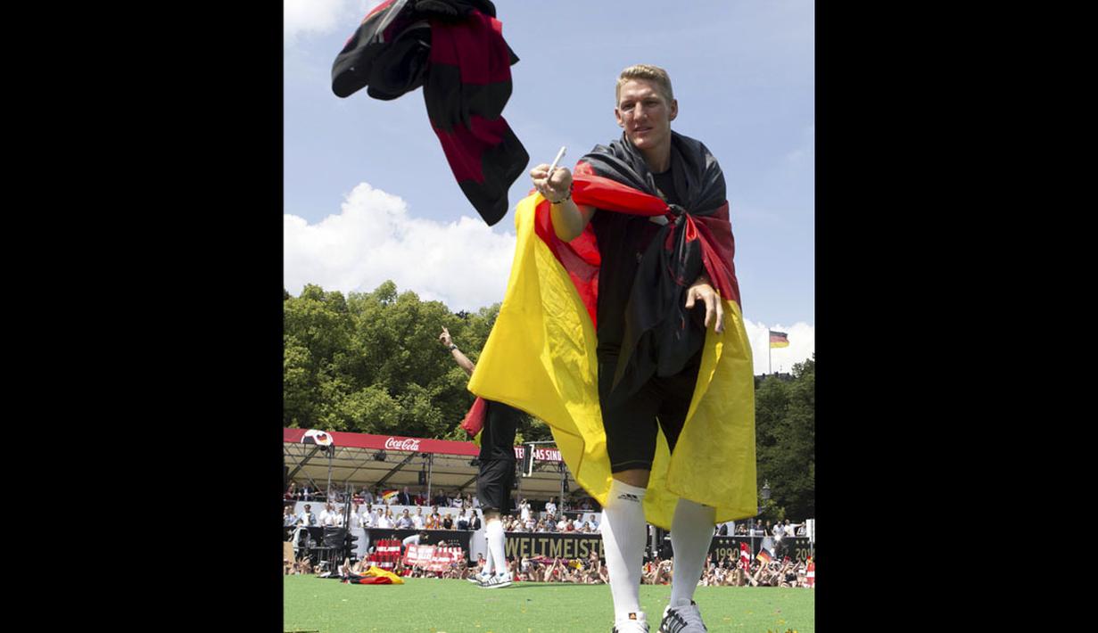 Pemain Timnas Jerman, Bastian Schweinsteiger, melemparkan kaos ke arah para suporter yang ikut merayakan kemenangan Der Panzer, Berlin, (15/7/2014). (REUTERS/Axel Schmidt)