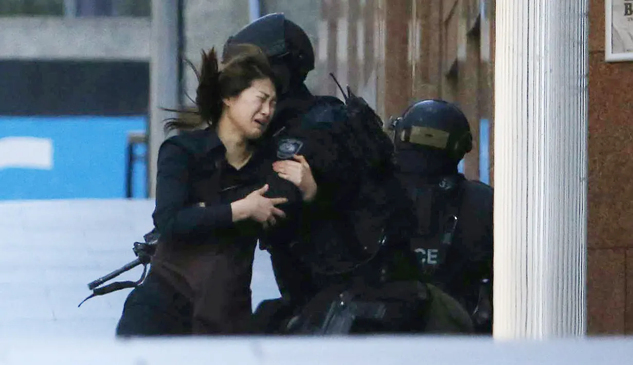 Seorang sandera berlari ke arah polisi setelah berhasil keluar dari Kafe Lindt, Martin Place, Sydney, Senin (15/12/2014). (REUTERS/Jason Reed)