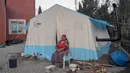 Seorang wanita duduk di depan tenda daruratnya di desa Yaylakonak distrik Adiyaman, Turki, Minggu (19/2/2023). 108 jiwa meninggal dan 170 rumah ambruk di Desa Yaylakonak distrik Adiyaman, Turki akibat gempa berkekuatan 7,8 magnitudo yang terjadi pada 6 Februari lalu. (BULENT KILIC/AFP)