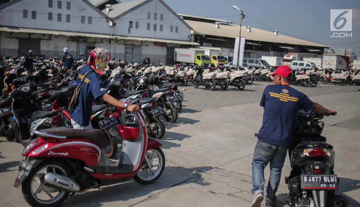 Pekerja membawa motor pemudik untuk dibungkus sebelum dikirim dengan kereta api di Stasiun Jakarta Gudang, Selasa (28/5/2019). Direktorat Lalu Lintas dan Angkutan Kereta Api Kementerian Perhubungan mengangkut 18.096 motor pemudik secara gratis pada mudik Lebaran 2019. (Liputan6.com/Faizal Fanani)