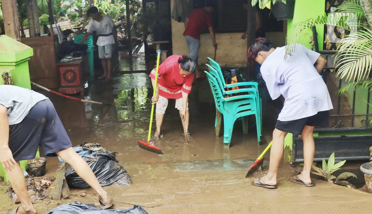 Warga membersihkan lumpur sisa banjir di halaman rumahnya di perumahan Ciledug Indah, Tangerang Senin (21/2/2021). Banjir yang menggenangi perumahan tersebut membuat warga mengalami kerugian cukup besar karena barang-barang berharga mereka rusak parah. (Liputan6.com/Angga Yuniar)