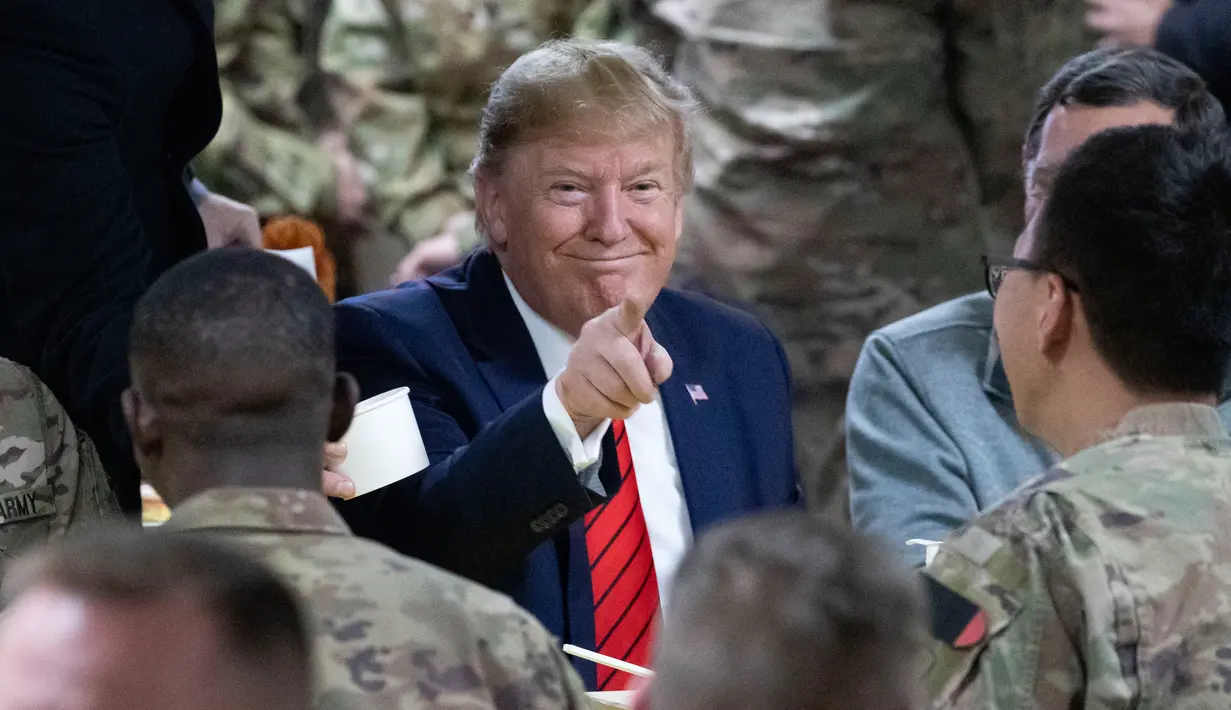 Presiden Amerika Serikat Donald Trump menunjuk sambil makan bersama para tentara di Pangkalan Udara Bagram, Afghanistan, Kamis (28/11/2019). Kunjungan dadakan Trump pada hari Thanksgiving tersebut mengejutkan pasukan AS yang bertugas di Afghanistan. (AP Photo/Alex Brandon)
