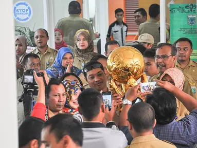 Para pegawai Pemerintah Kota Batu berebut foto dengan trophy Piala Bhayangkara 2016 di Malang, Jawa Timur, Selasa (11/4/2016). Kunjungan Arema Cronus ke Pemkot Batu menghasilkan bonus 100 juta rupiah. (Bola.com/Iwan Setiawan)