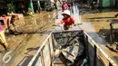 Seorang anak kecil terlihat duduk di gerobak barang bekas di komplek Pondok Gede Permai Jatiasih, Bekasi, Jumat (22/04). Tumpukan sampah akibat banjir menjadi rezeki tambahan bagi pemulung. (Liputan6.com/Fery Pradolo)