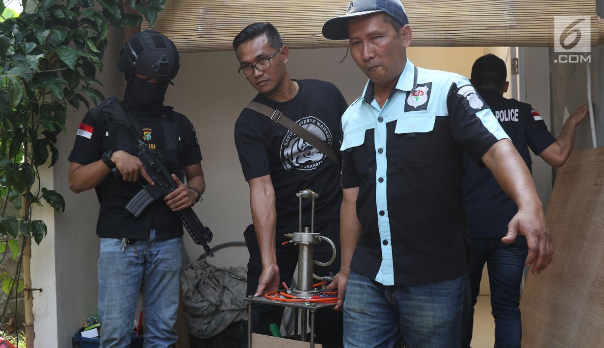 Petugas mengangkut barang bukti alat pencetak pil ekstasi di sebuah perumahan di Kawasan Pondok Rajeg, Cibinong, Jawa Barat, Senin (24/9). Polisi juga menahan tiga tersangka dan sejumlah barang bukti terkait. (Liputan6.com/Helmi Fithriansyah)