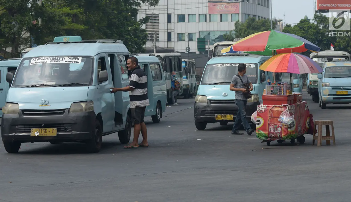 Pedagang kaki lima menjajakan dagangannya di depan angkot yang menunggu penumpang di Terminal Kampung Melayu, Jakarta, Jumat (2/8/2019). Gubernur DKI Anies Baswedan melalui Kepala Dinas Perhubungan menyiapkan rancangan peraturan daerah tentang pembatasan usia kendaraan. (merdeka.com/Imam Buhori)